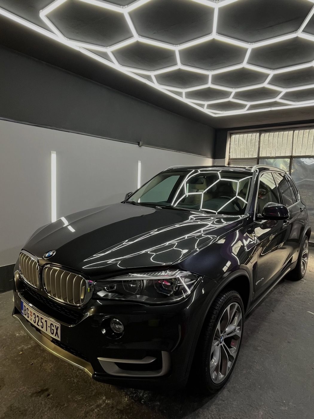 Crni BMW X5 posle poliranja ispod heksagonalnih svetala